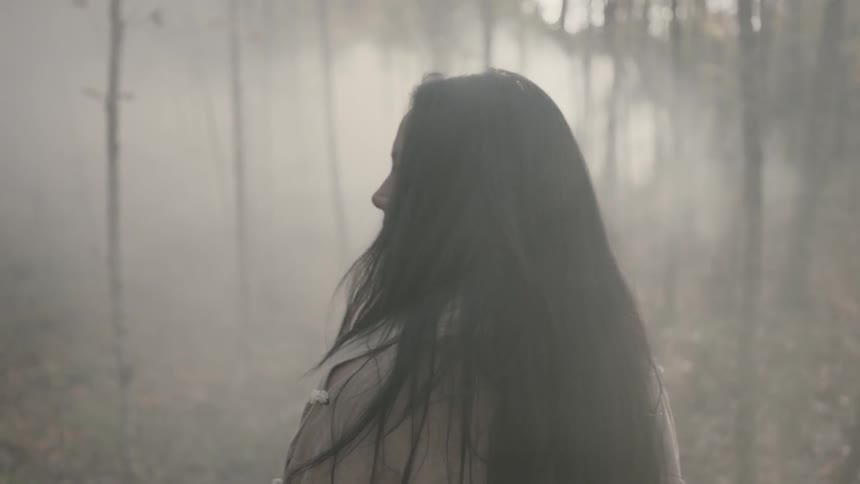 A woman is walking in foggy woods