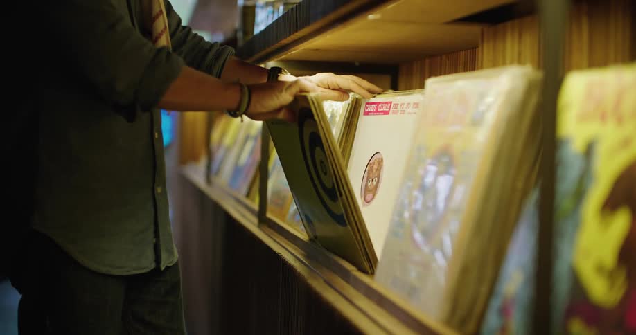 A man is searching through vinyl records albums in a store