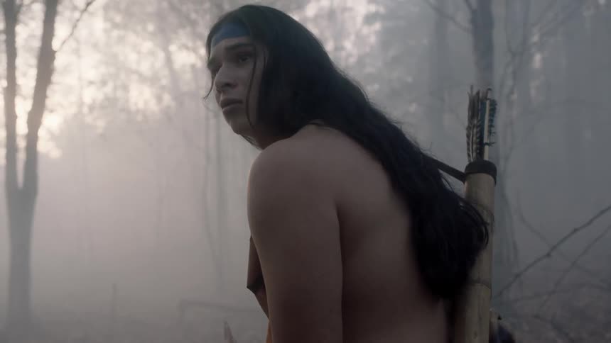 Tribal man looking cautiously around in a smoky wooded area