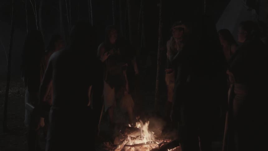 People stand around a fire at night
