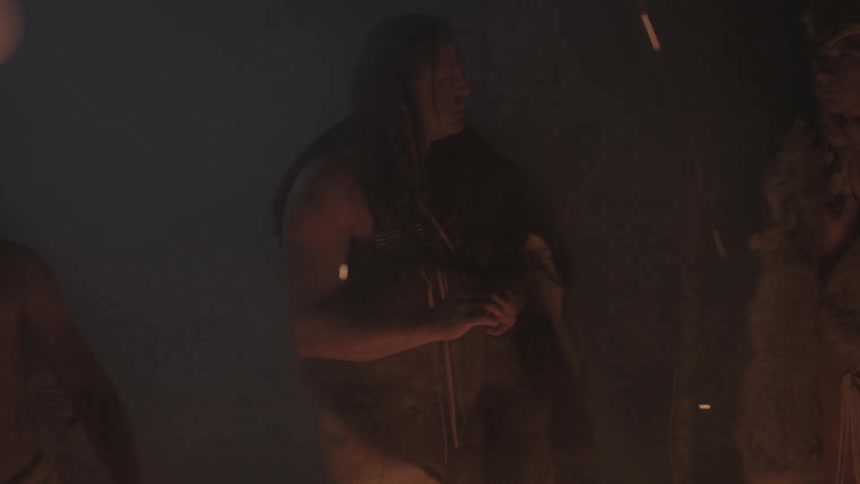 Tribal people standing around a campfire
