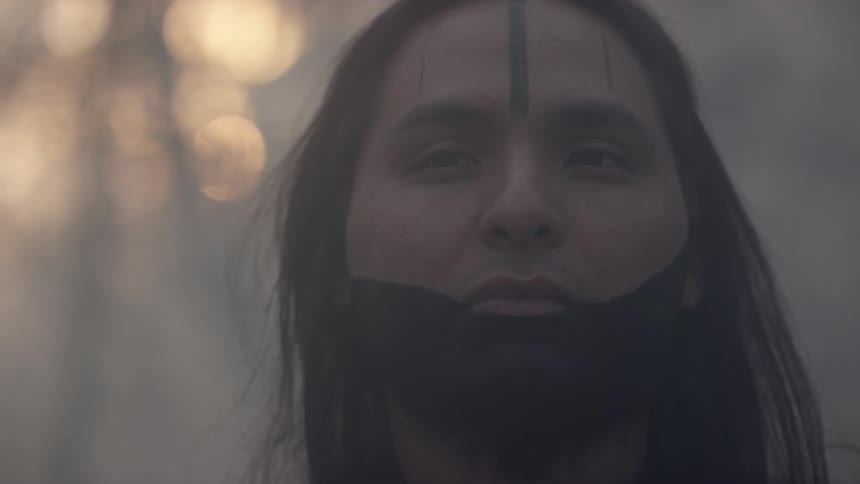 Close-up of a tribal person's face with black paint in the forest