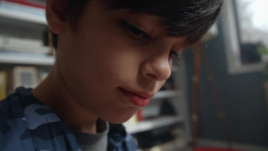 Light shines on the face of a little boy as he is in a room looking at something