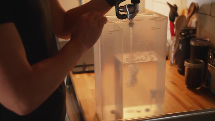 A man fills a pitcher with water at home