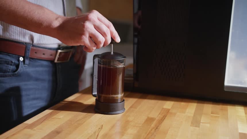 Man uses cold press to make his beverage while standing at home