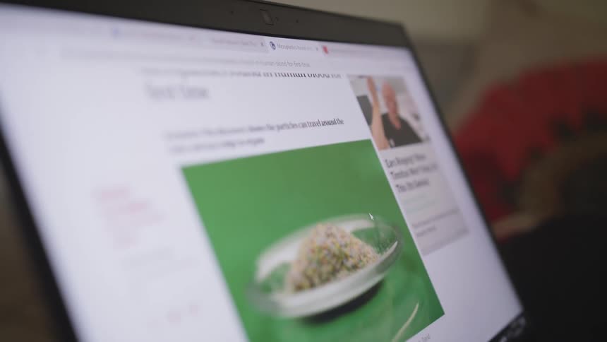 Close up of a person scrolling through an article on a website on the screen of a laptop
