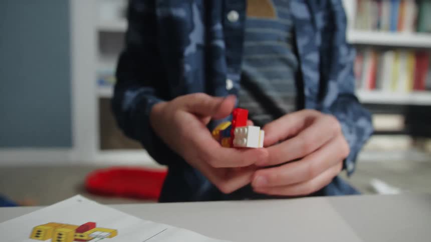 Young boy reading the instructions to assemble a lego set in his bedroom