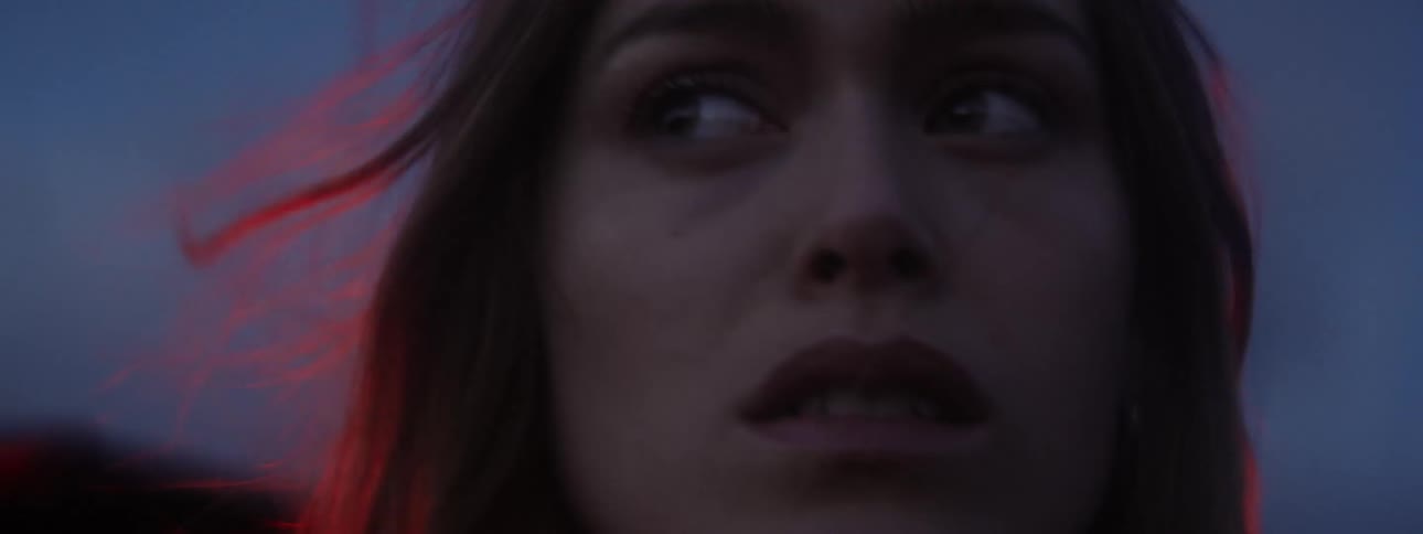 Close up of the face of a frightened woman having her hair blown by the wind at evening