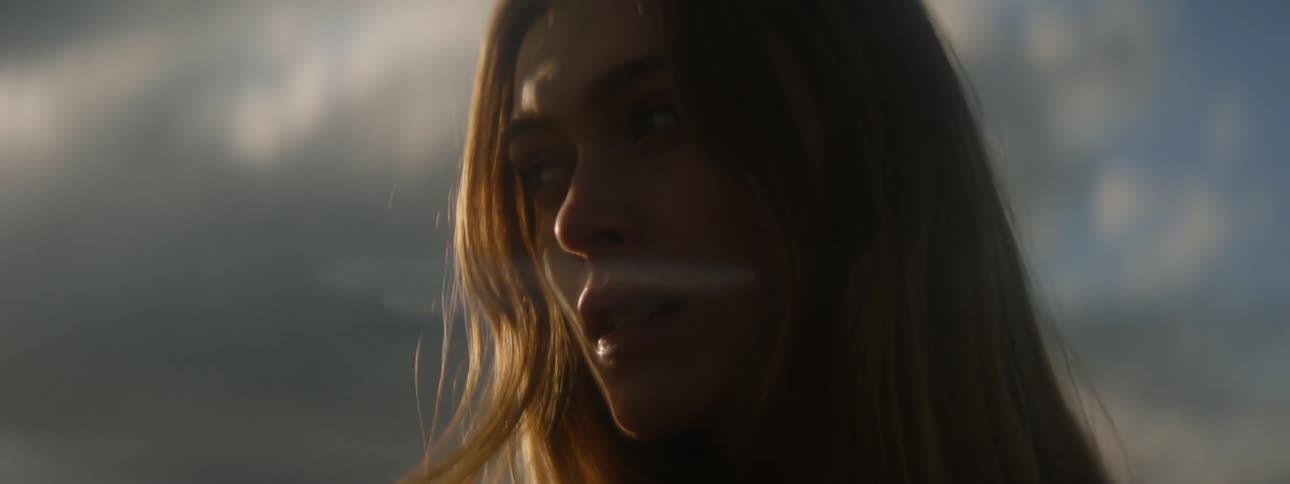 The sun shines on womans face looking over her shoulder