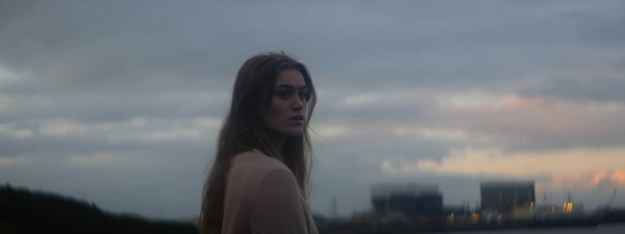 A woman is standing outdoors at dusk