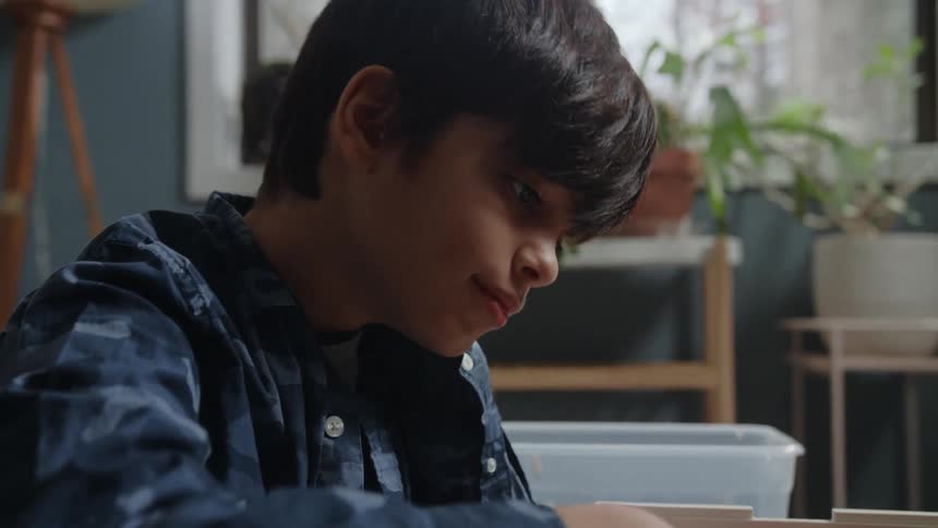 Boy sits combing through contents in box with a slight smile