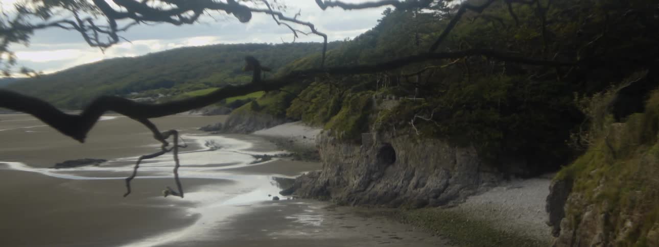 Water is pooled on a beach with cliffs