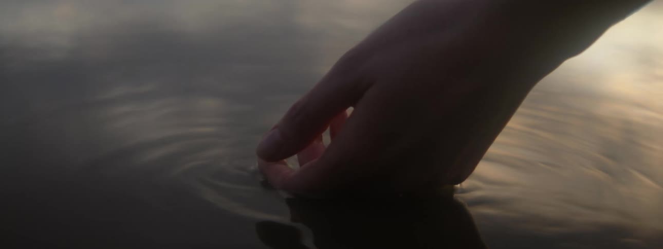 A woman touches the sea with the back of her hand