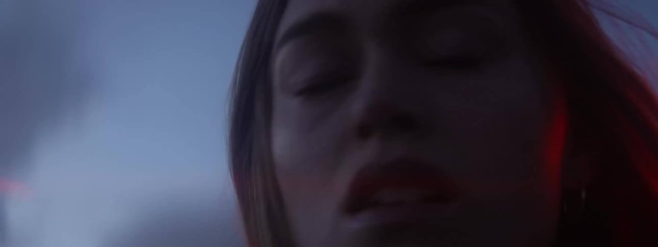 A woman turns her head looking back into a glowing red light