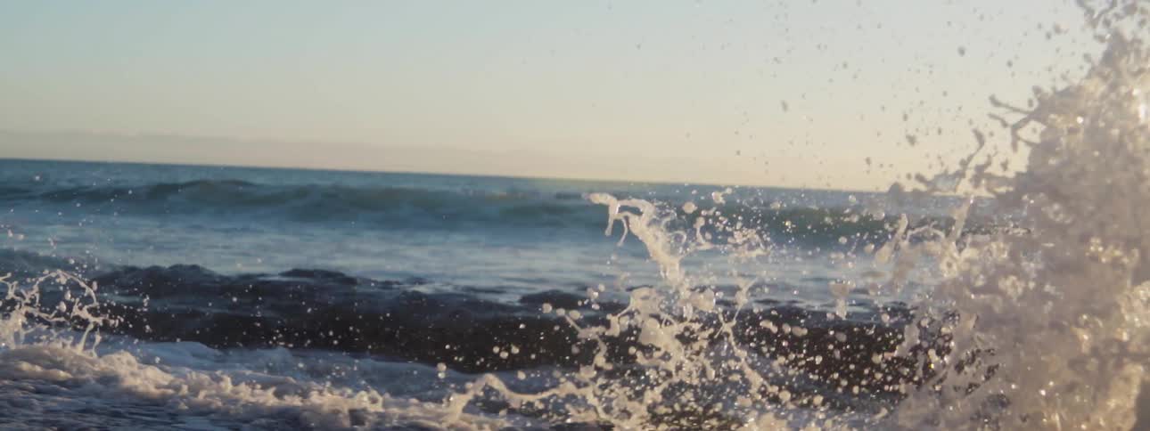 The wave crashes against the rocks