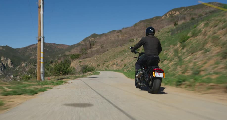 Man rides a motorcycle downhill on a road on the mountains at daytime