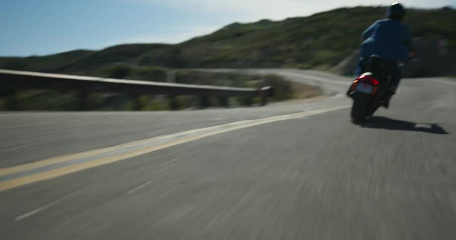 Man rides a scooter downhill on a road on the mountains at daytime