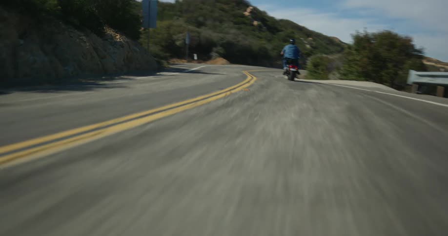 Man riding a motorcycle uphill on a road on the mountains at daytime