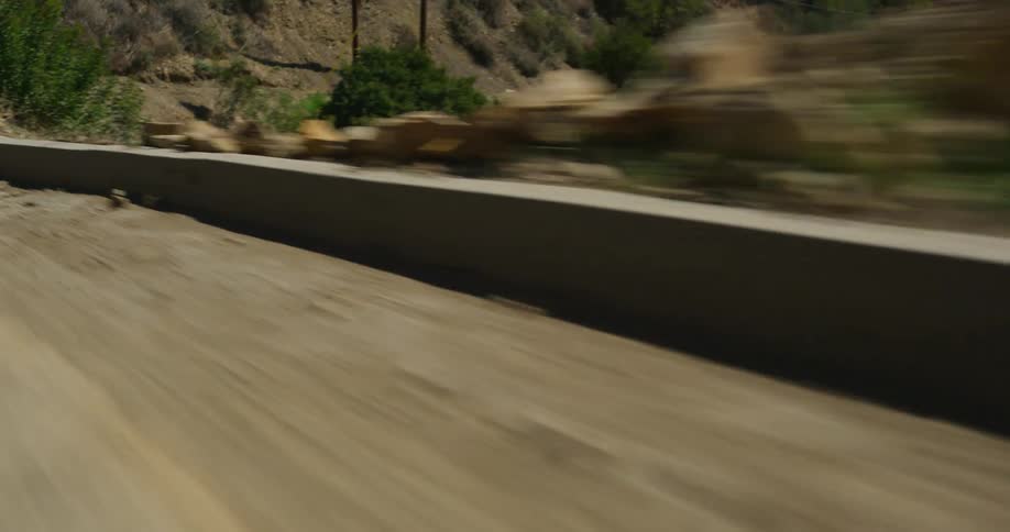 The camera speeds along a winding road as it bends back and forth