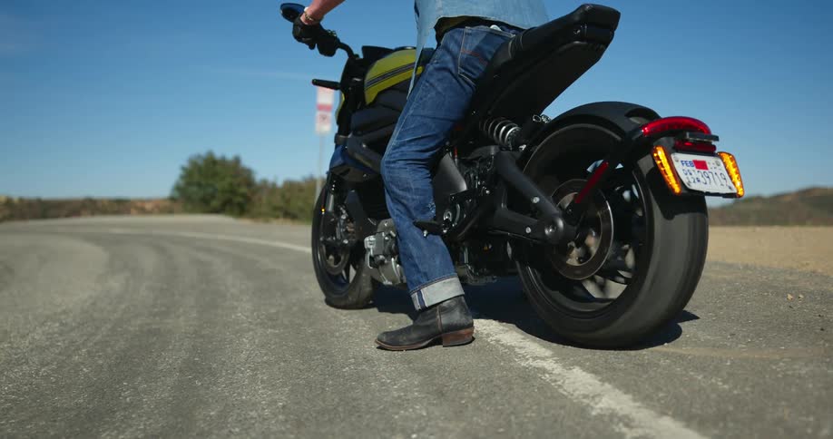 A man revs his motorcycle while parked in the road