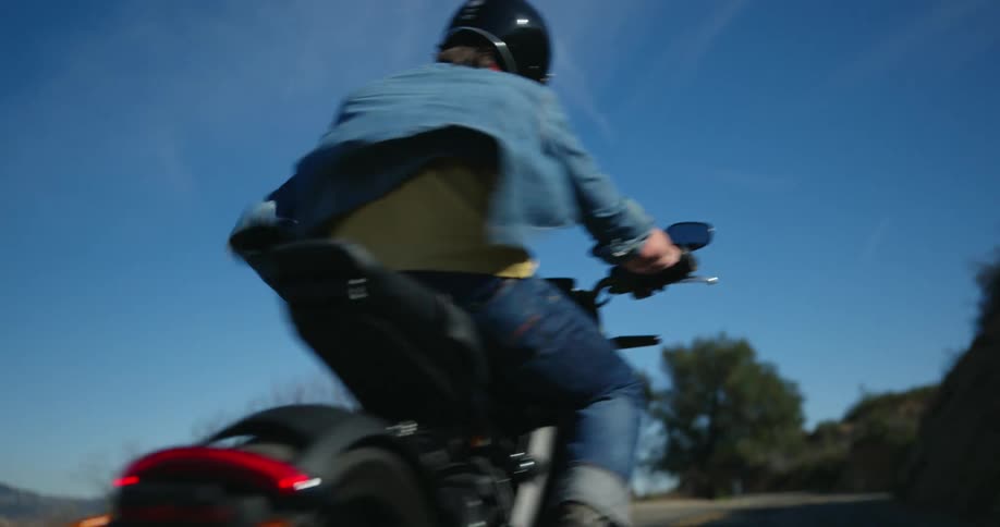 Man rides a motorcycle downhill on a road on the mountains at daytime