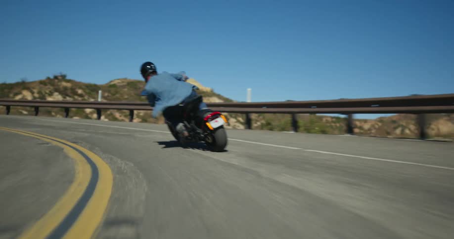 A person rides a motorcycle along a countryside road on a clear day