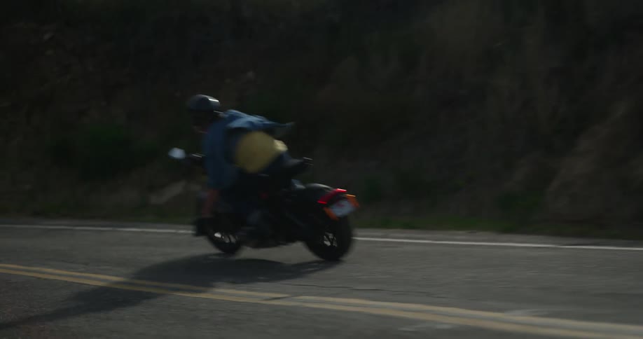 A motorcycle rider travels around a curve on a mountain road