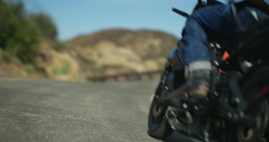 A man wearing denim apparel steers his motorcycle along a winding road