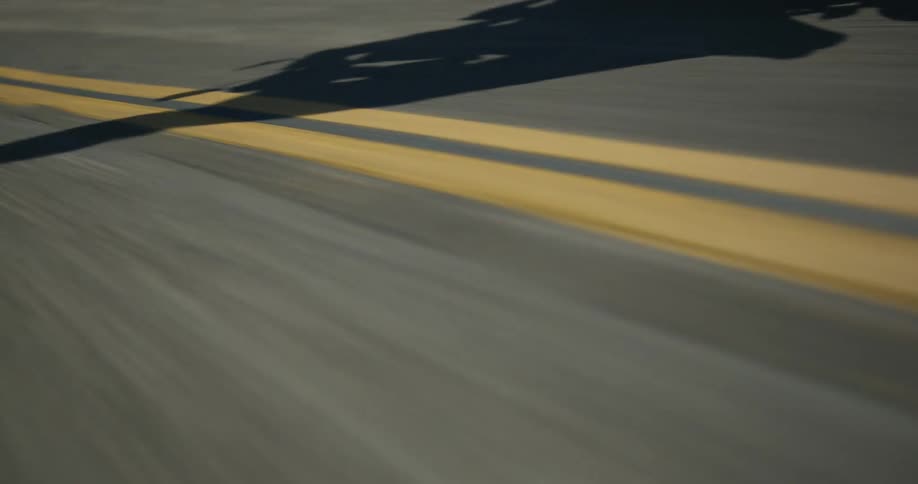 A person rides a motorcycle along a winding mountain road on a sunny day