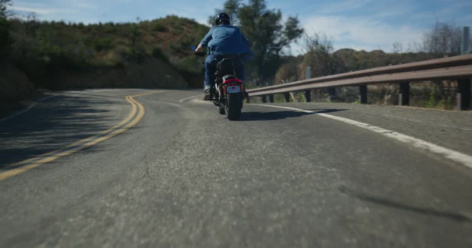 A cyclist is sitting on a motorcycle spinning the back tire before taking off on a mountain road