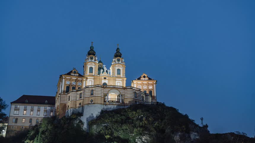 Time lapse of a castle or fort atop a hill turning on lights as night falls