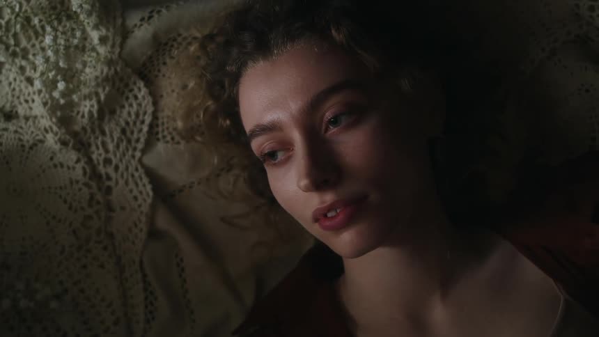 Close up of the face of a beautiful woman resting on a bed opening her eyes