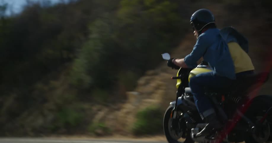 A man wearing denim apparel steers his motorcycle along a very curvy road