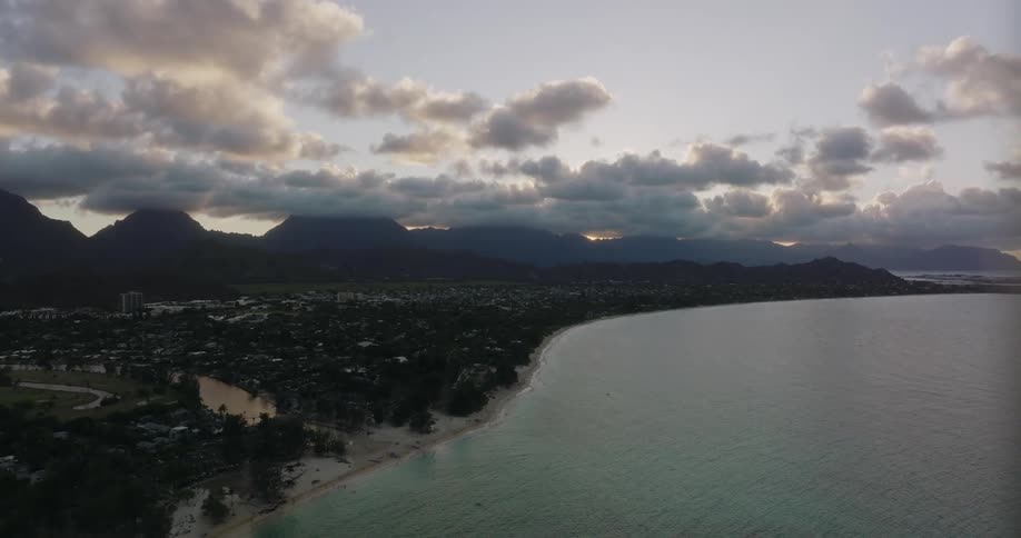 Channel flows from shore through large town bounded by misty mountains on a cloudy day