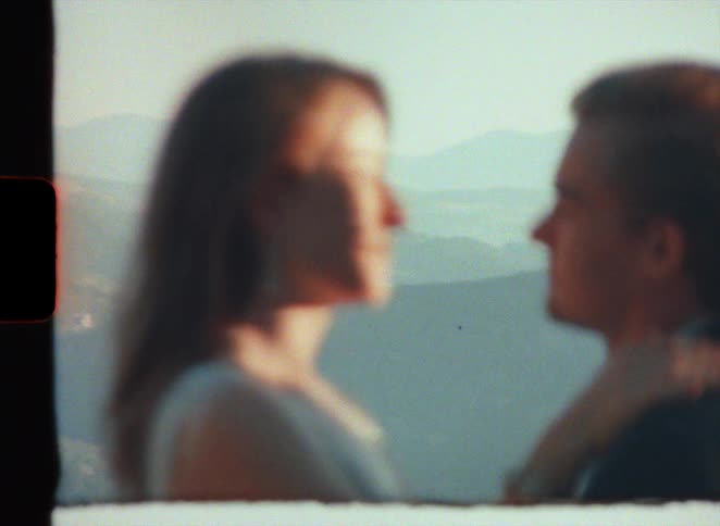 Groom with suit makes out with bride wearing wedding dress on high mountain in super 8 film