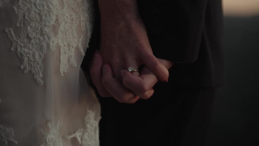 Bride wearing her gown and groom stand holding hands