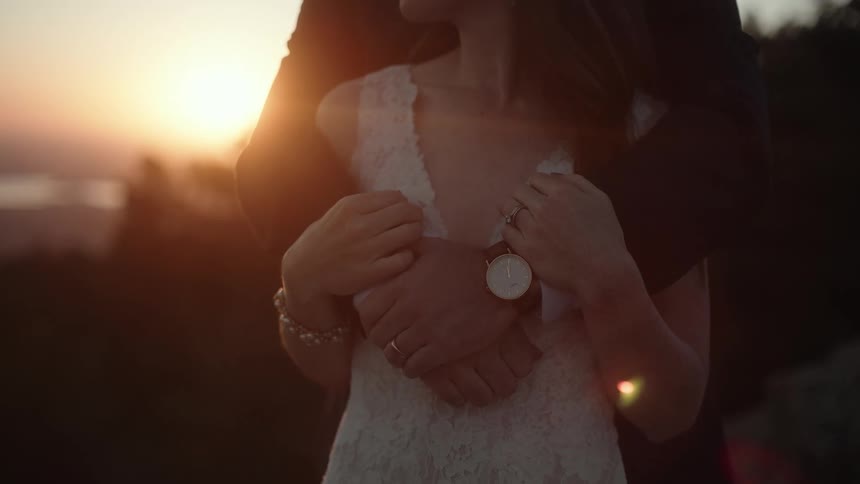 A man in a suit wraps his arms around a woman in a wedding dress