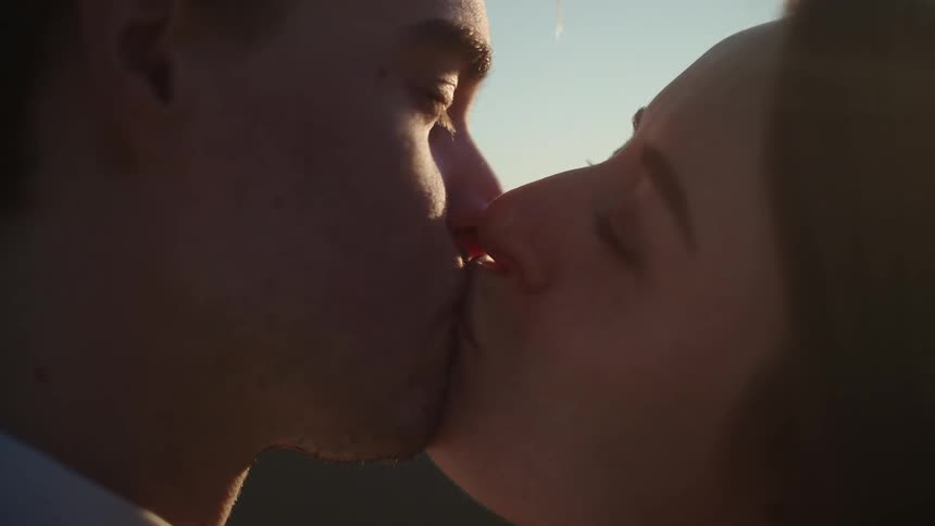A man and woman kissing outside