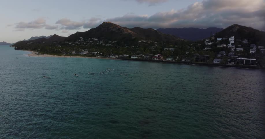 People are in canoes on a lake near a town in the mountains
