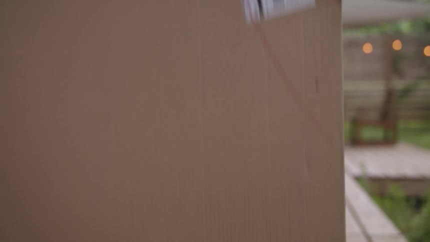 Man picks up a cardboard box from the porch and brings it into the house