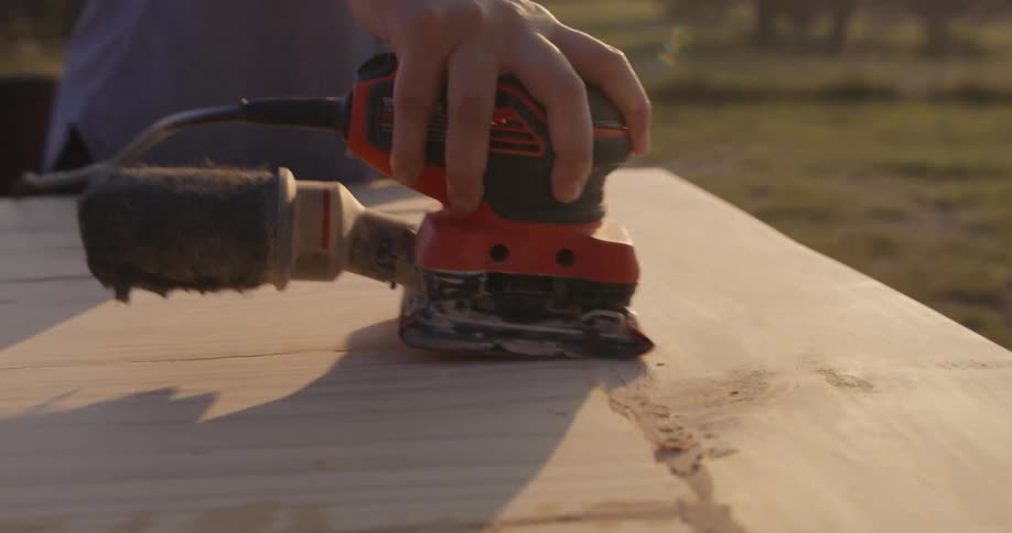 A woman sands wood outside