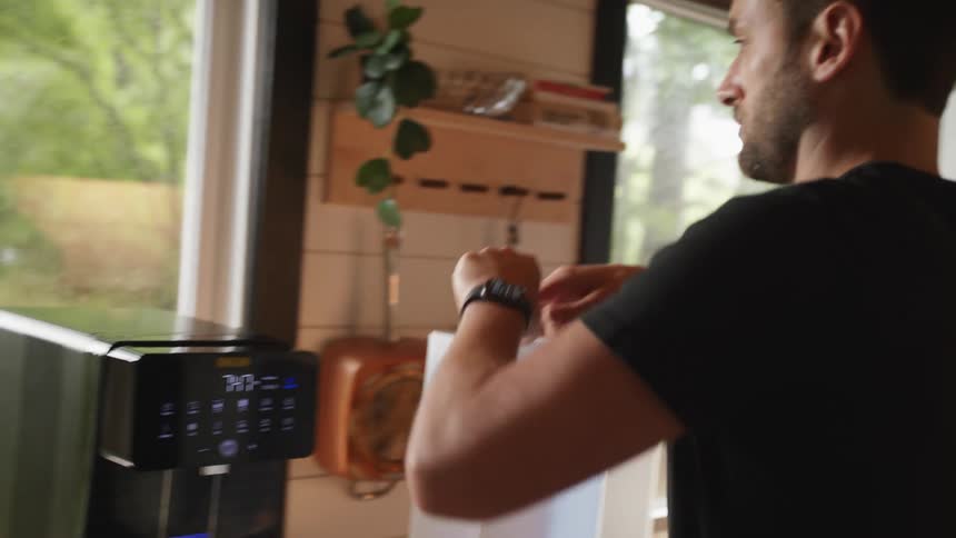 A man fills the water reservoir of a fancy coffee maker before attaching it