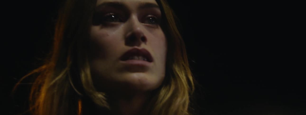 Orbiting close up of a fearful woman standing on a street at night