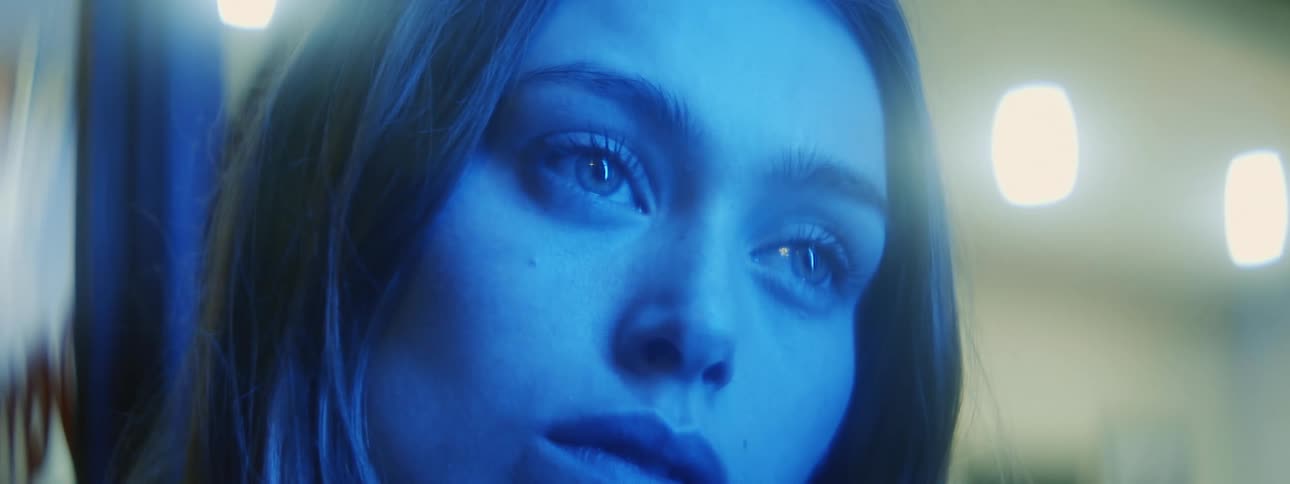 Blonde womans face in blue light looks into space