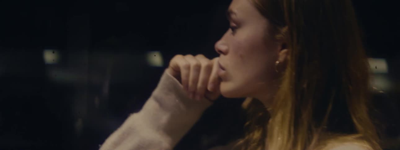 A woman looks out the window of a bus at night