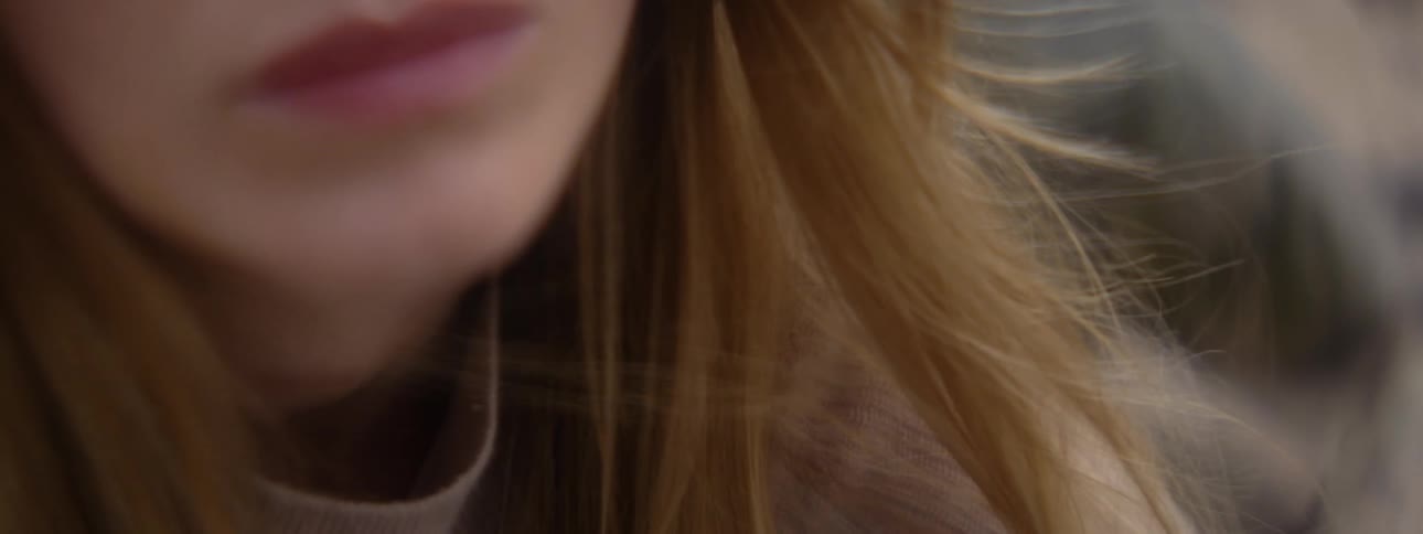 Wind blows womans hair about her mouth and chin
