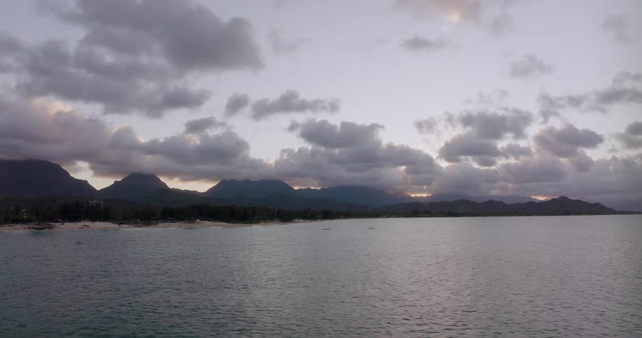 A landscape view of and ocean and beach with hills in the distance