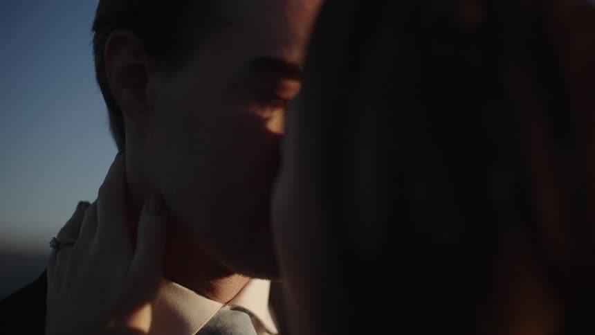 Wedding couple slowly kissing outdoors