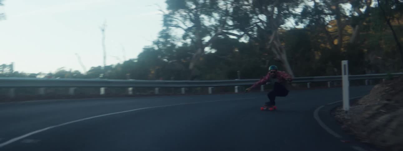 Man rides a skateboard in downhill on a road at morning