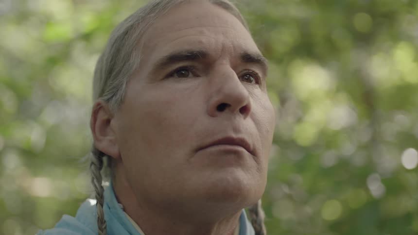 Tribal man slowly raising his head and looking forward solemnly in the wilderness